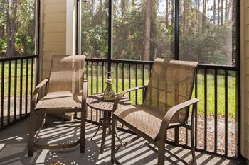 a porch with two chairs and a table on a balcony
